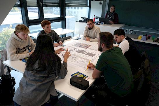 Erstsemester sitzen an einem Tisch und planen ihre Stadt
