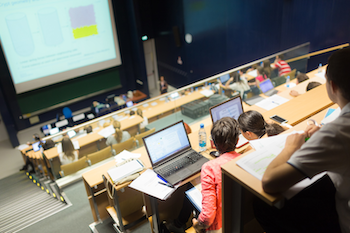 Studierende im Hörsaal während einer Vorlesung mit Präsentation an der Leinwand