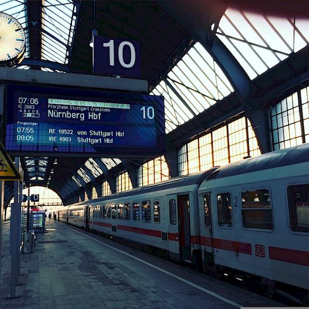 Ein Bahnhof mit einer Anzeigetafel, auf dessen Anzeige der Zug nach Nürnberg HBF angekündigt wird.